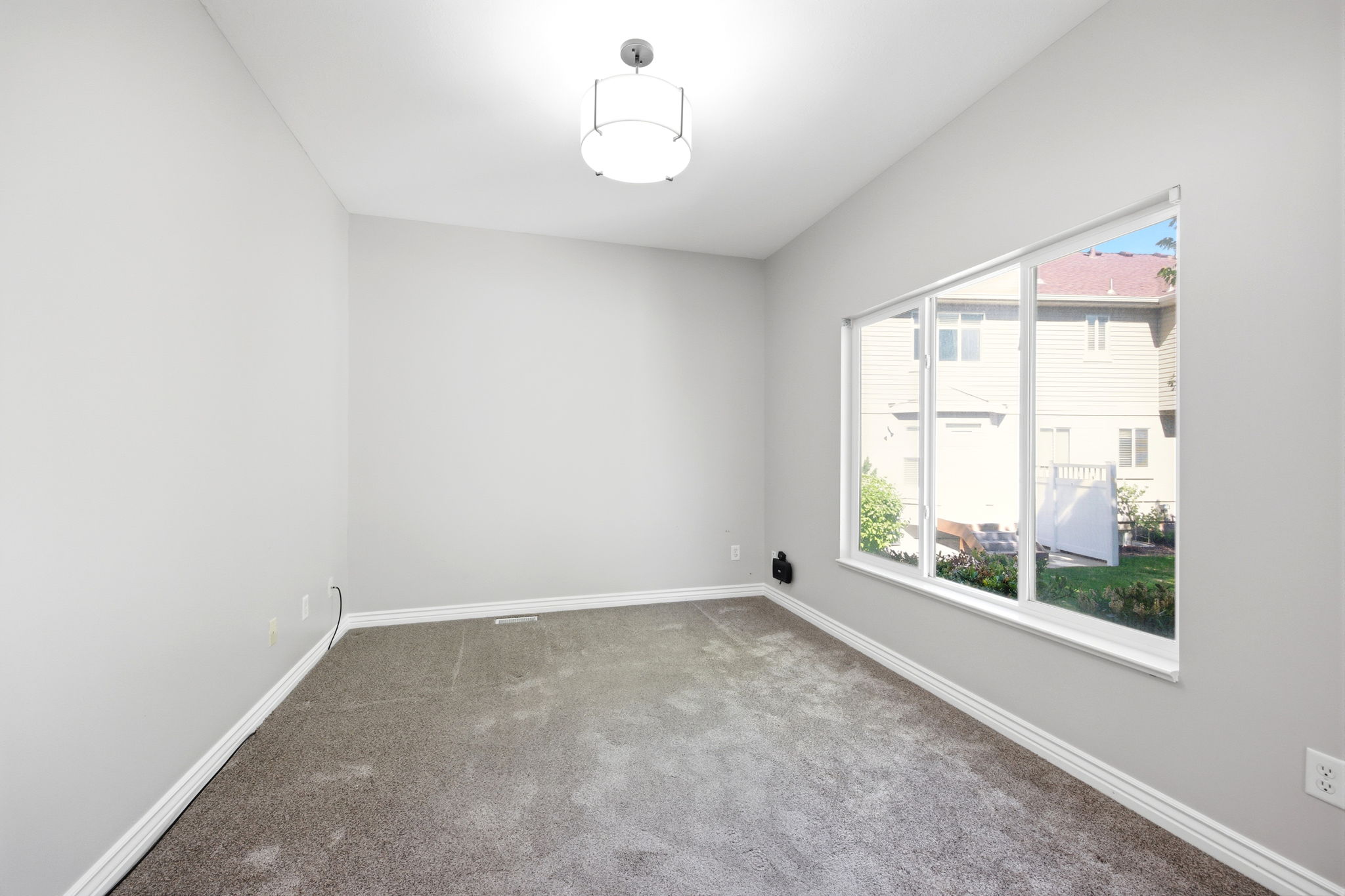 Bright interior space featuring light gray wall paint, white baseboards, and a contemporary flush-mount ceiling light