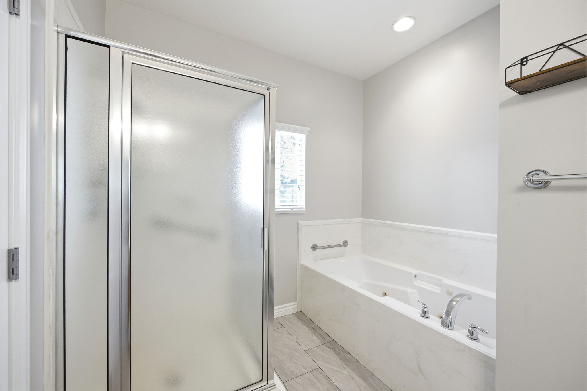 Full bathroom featuring a glass-enclosed shower, a built-in soaking tub with a marble-finish surround, contemporary chrome fixtures, and recessed lighting