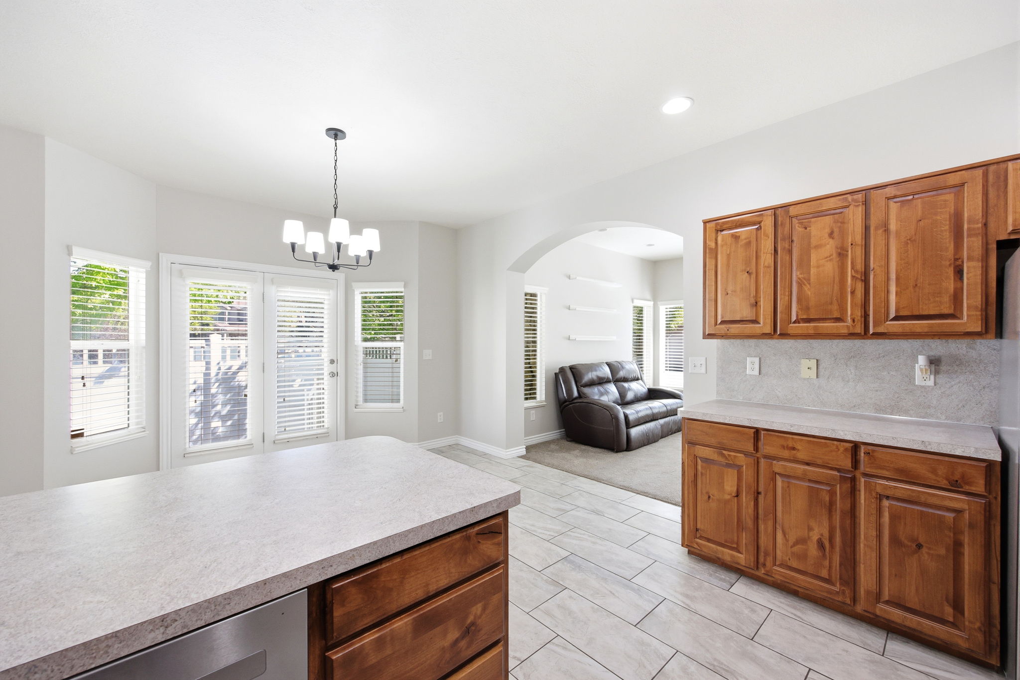 Kitchen featuring warm wood cabinetry, light-toned countertops, and a full tile backsplash