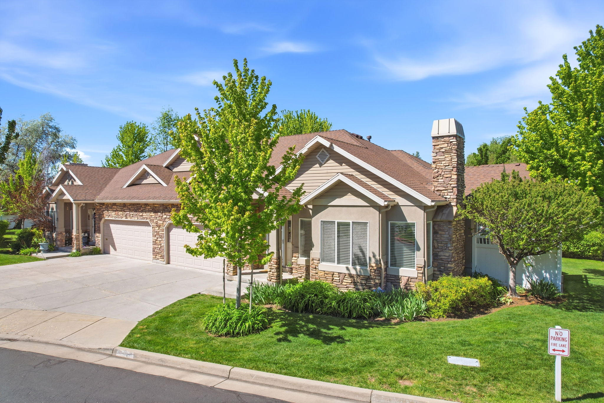 Spacious residence featuring a two-car garage, stone and siding exterior, and a prominent stone chimney
