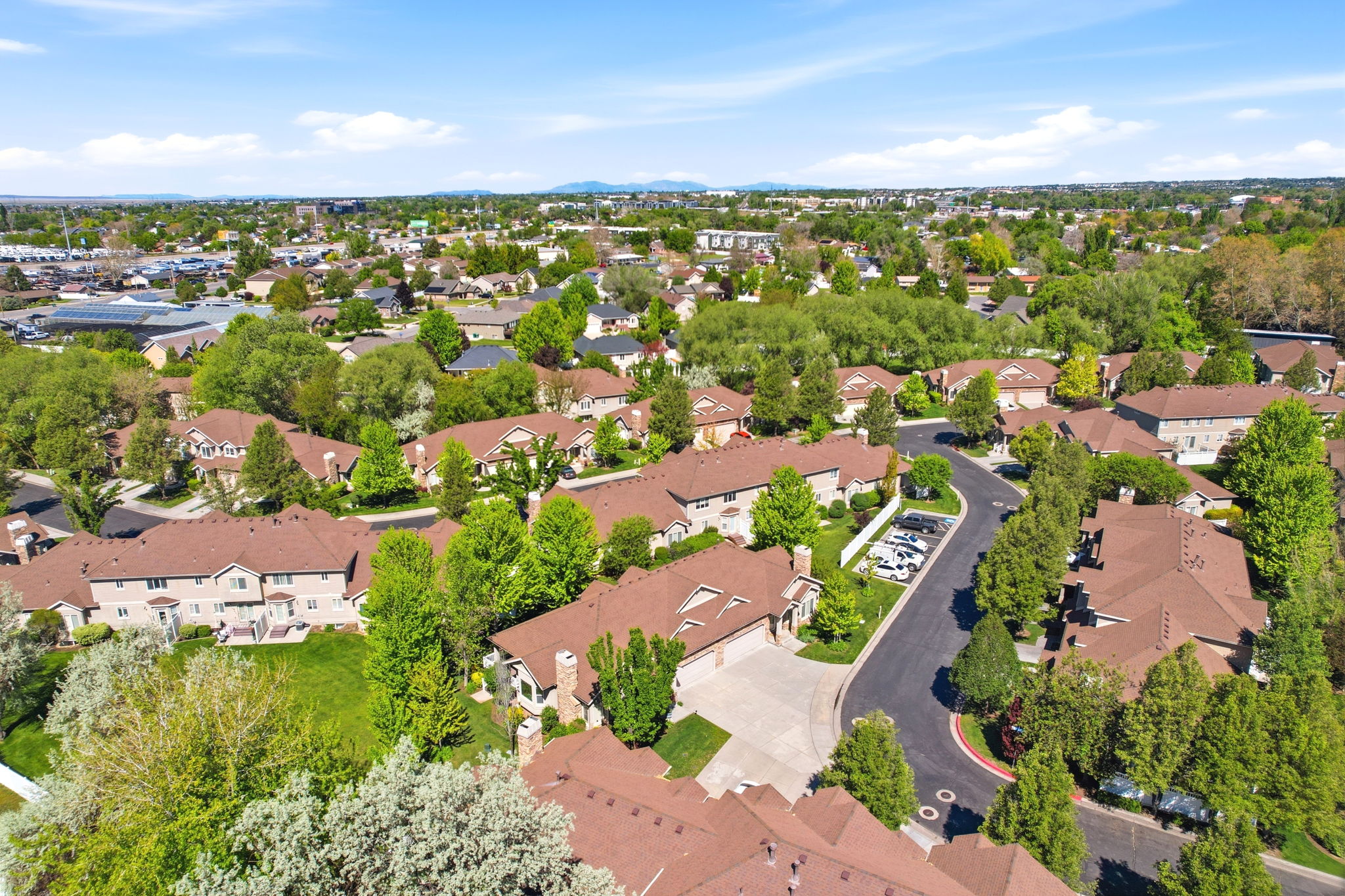 Aerial perspective showcasing a residential community with numerous brown-roofed structures, surrounded by mature green trees