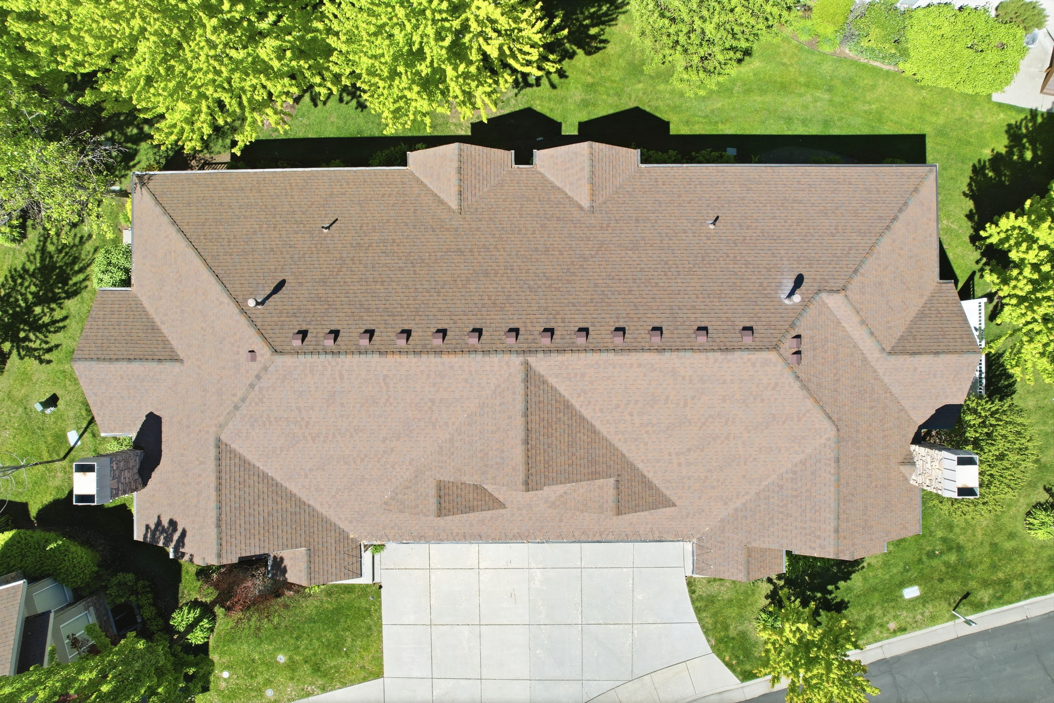 Expansive property featuring a brown shingle roof, multiple gables, and a concrete driveway