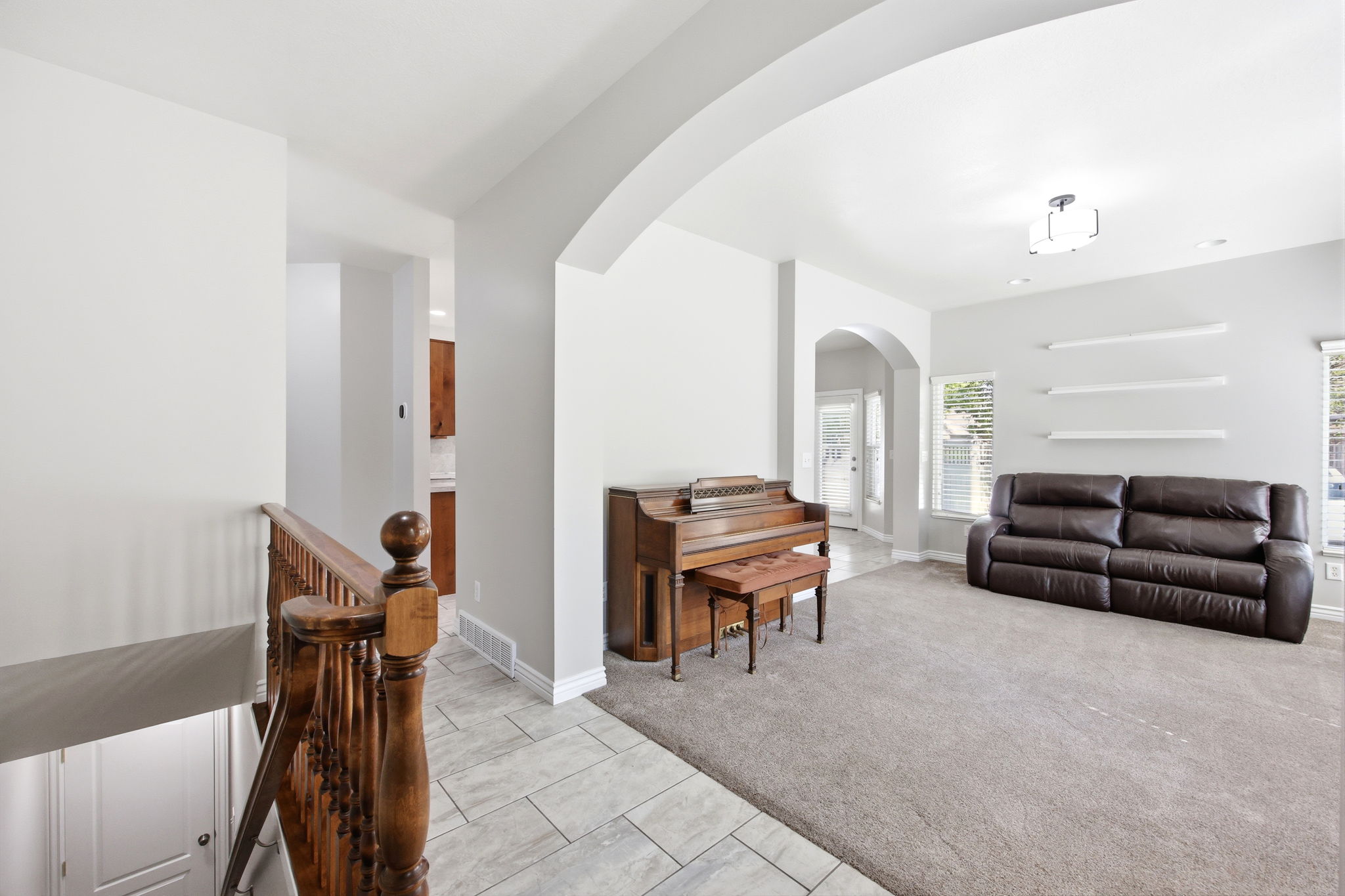 Archway entry to a carpeted living space featuring recessed lighting and wall-mounted shelving