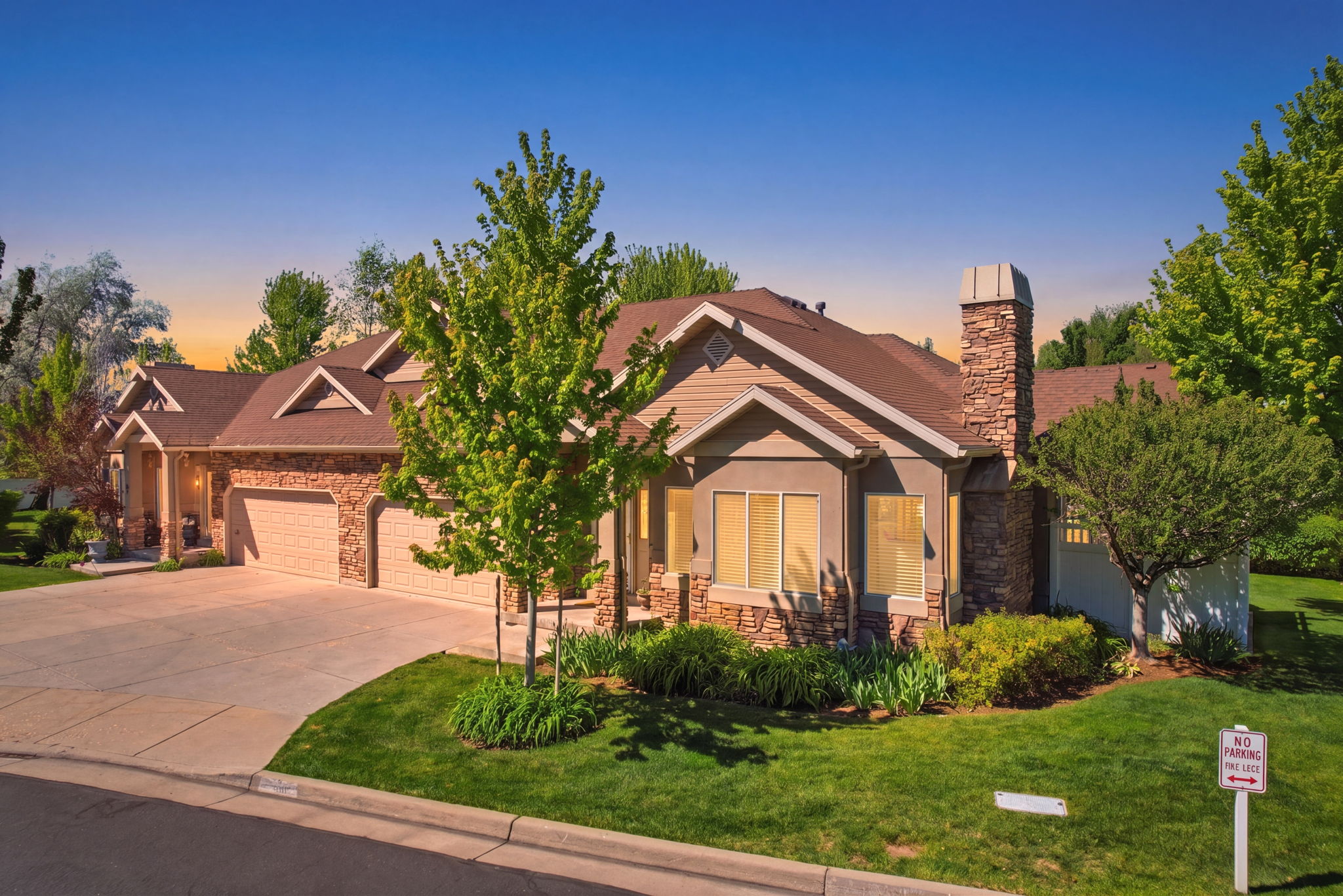 Crafted exterior featuring stone and siding finishes, multiple gabled rooflines, an attached two-car garage, and a stone chimney