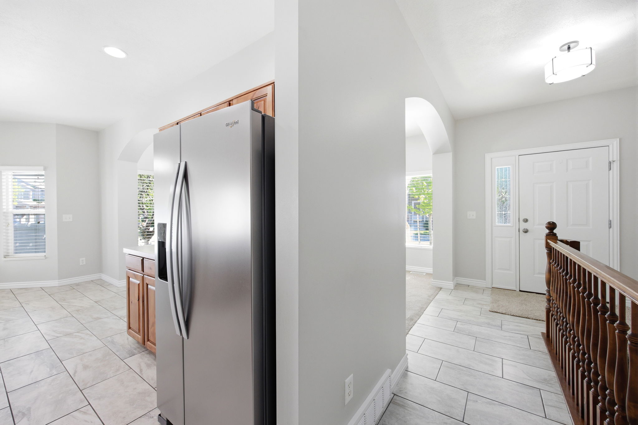 Stainless steel refrigerator with a built-in water and ice dispenser, light wood cabinetry, and recessed lighting