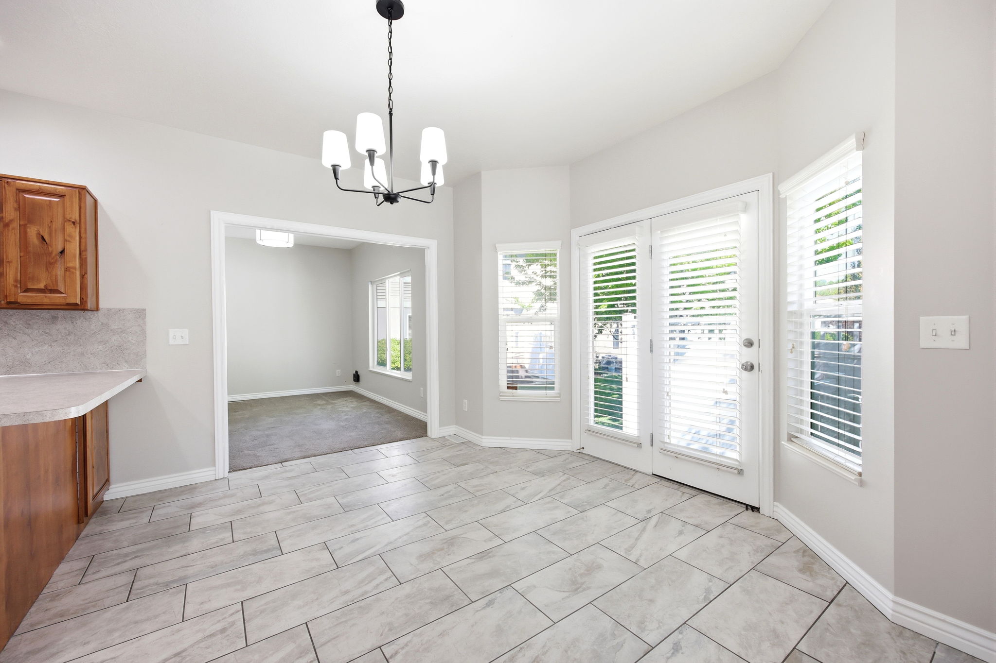 Bright dining area featuring tile flooring, a modern chandelier, and access to an outdoor space through double doors