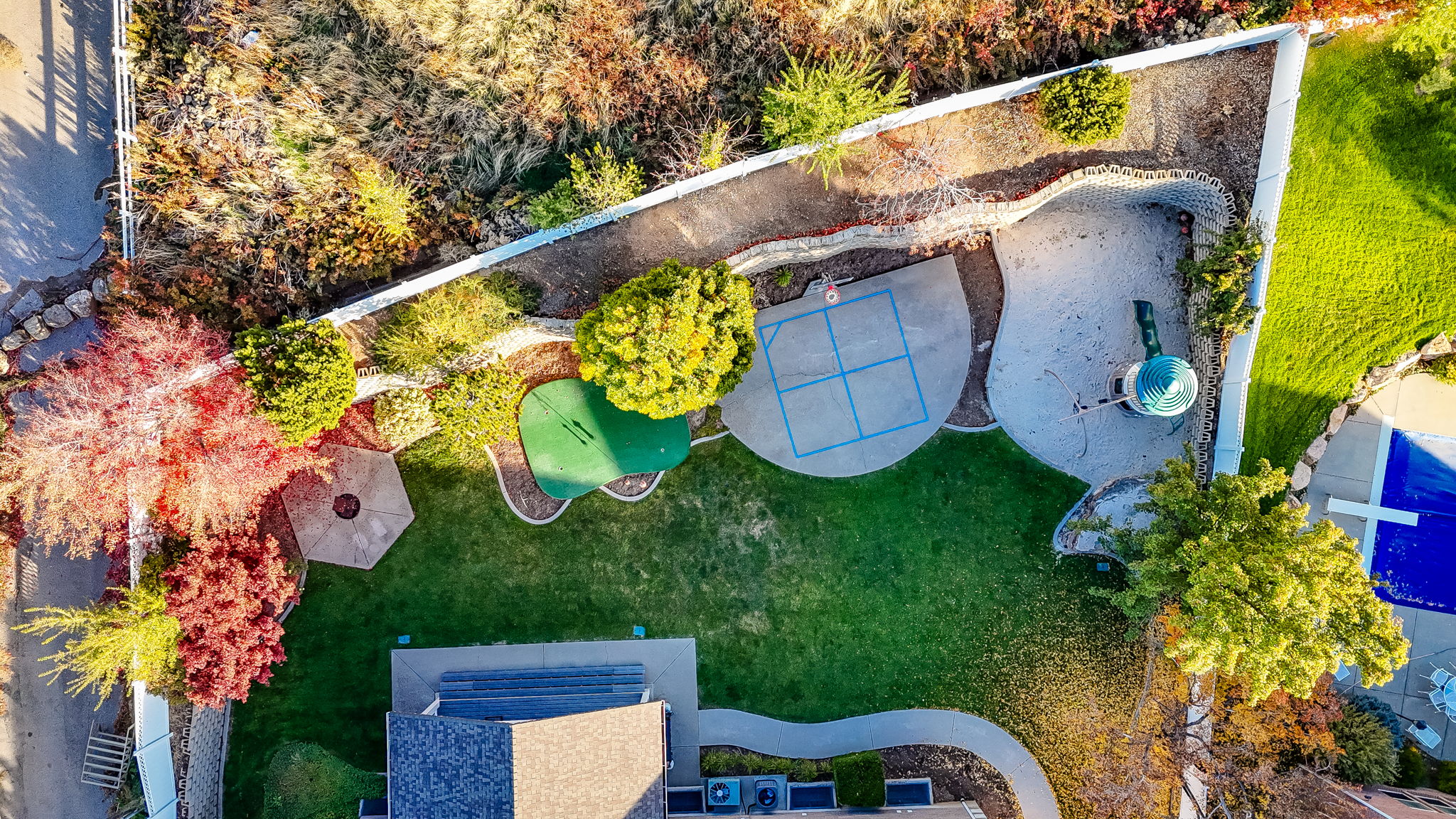 Expansive backyard featuring a lush lawn, mature landscaping, and a covered swimming pool
