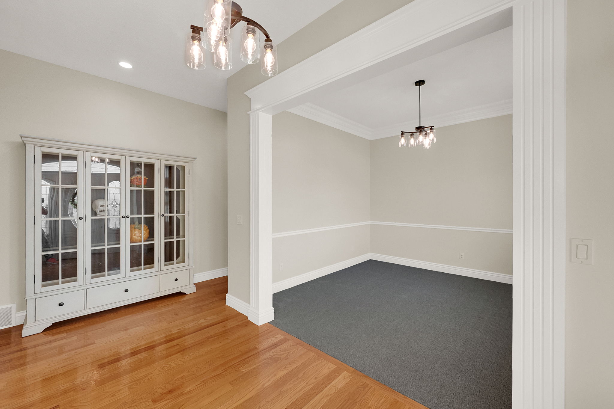 Hardwood-style flooring extends into an entryway featuring a modern chandelier and recessed lighting