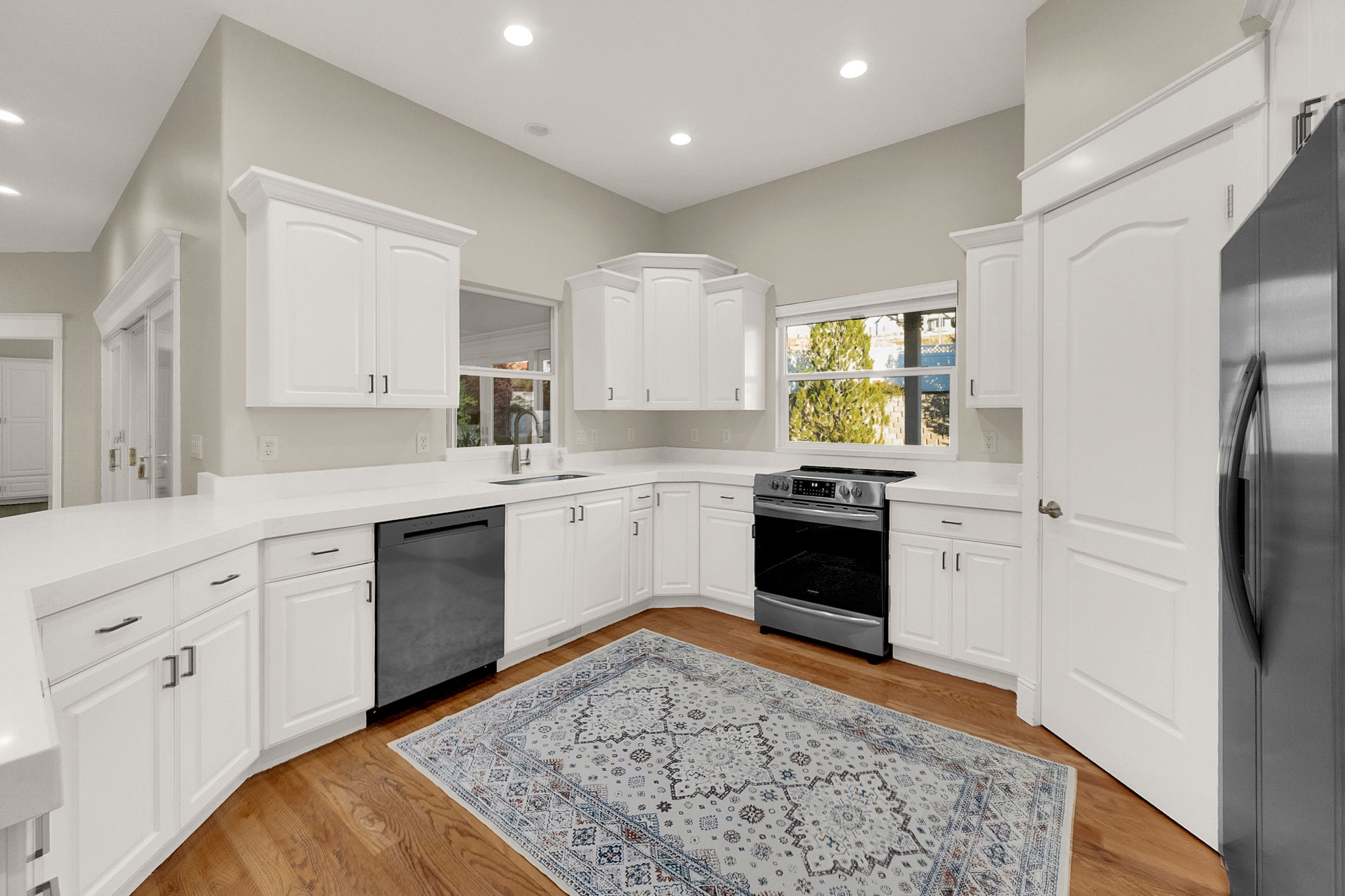 Spacious kitchen featuring white cabinetry, light-toned countertops, and wood-finish flooring