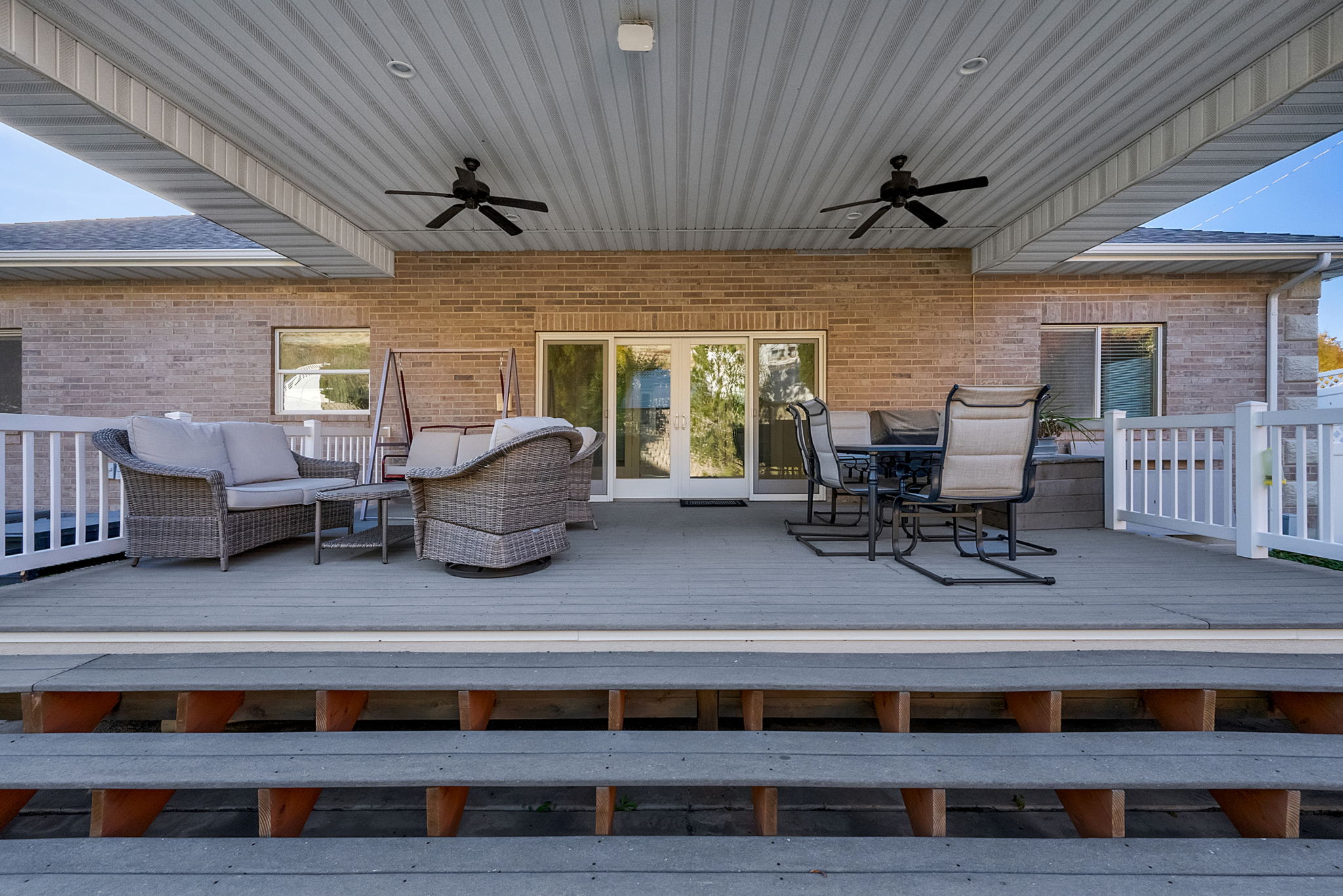 Expansive covered deck featuring a textured surface and multiple ceiling fans