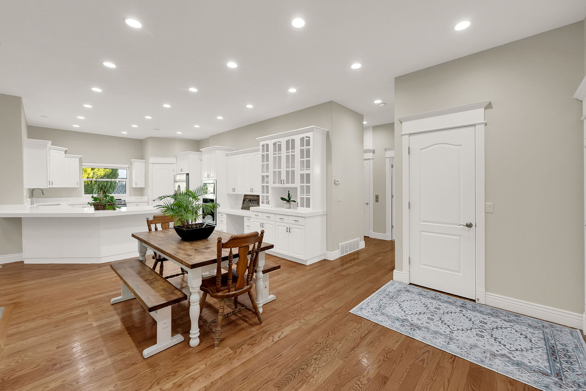 Expansive open-concept space featuring wood-finish flooring, recessed lighting, white cabinetry, and white countertops