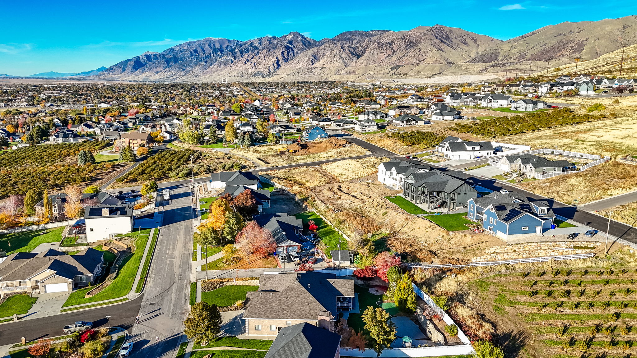 Expansive residential area featuring established homes, new construction, paved streets, and mountainous terrain