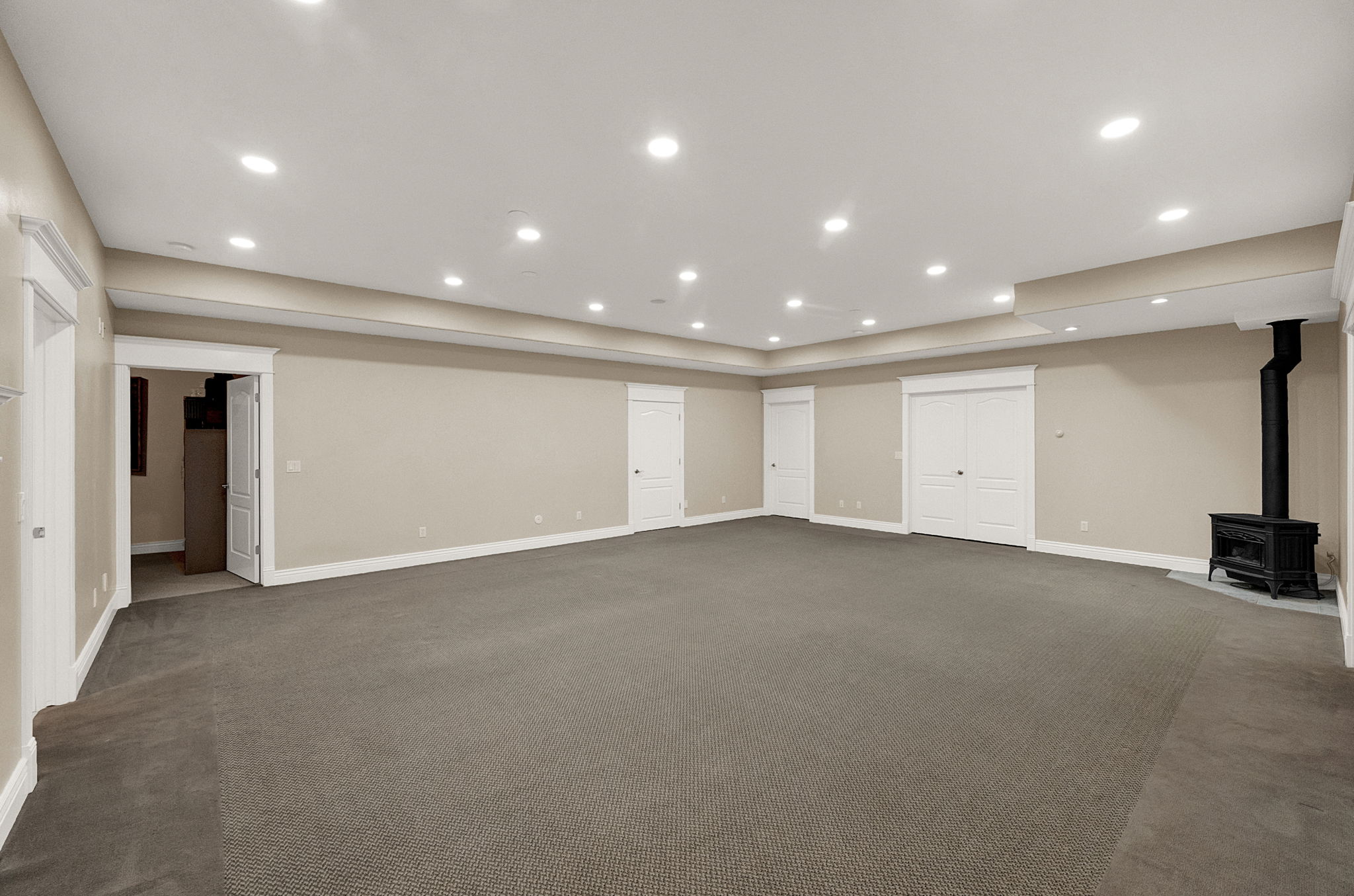 Spacious room featuring neutral paint, recessed lighting, and a cast iron stove with a dark flue