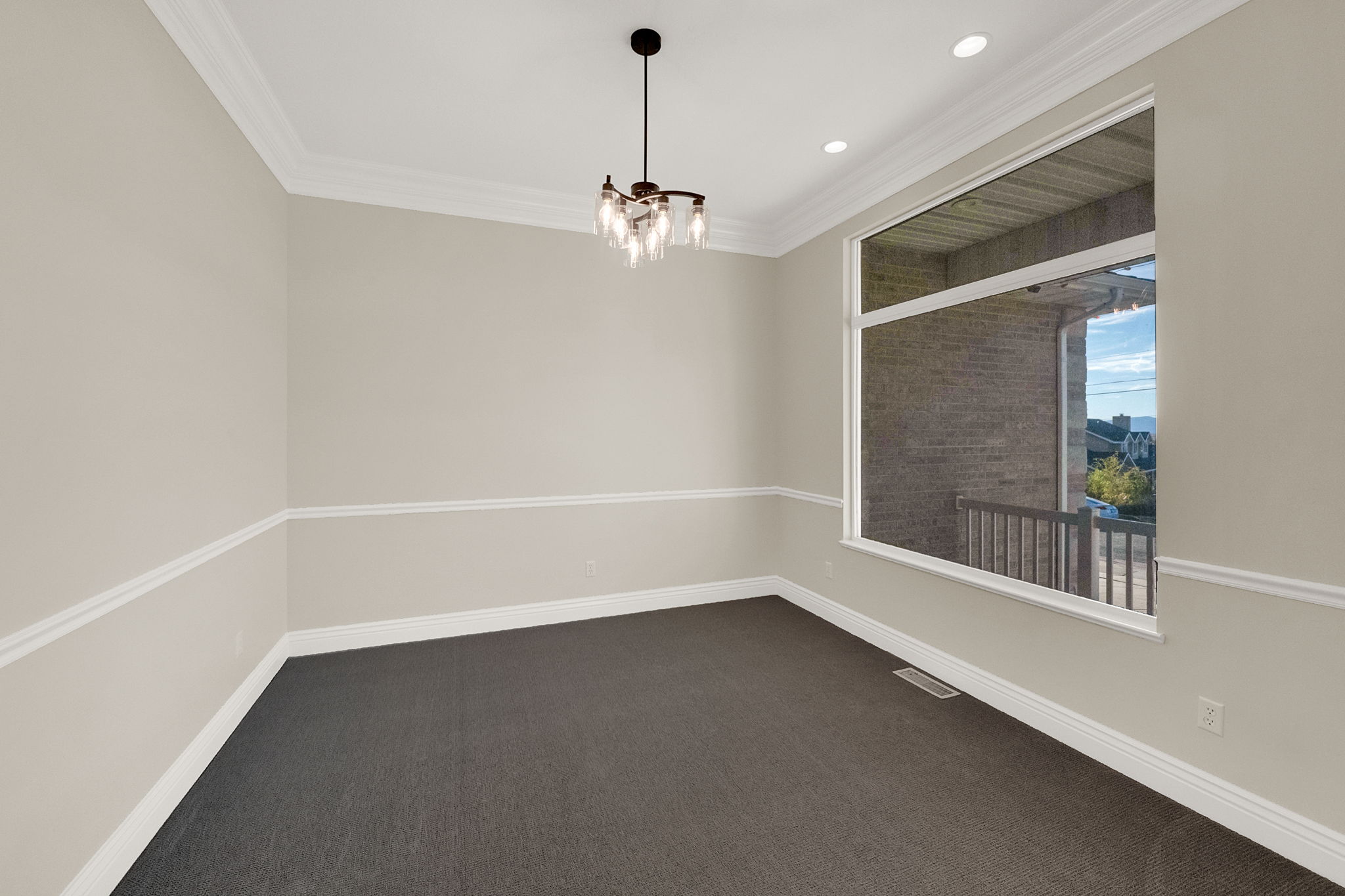 Formal room featuring crown molding, neutral wall tones with chair rail detailing, recessed lighting, and a modern chandelier