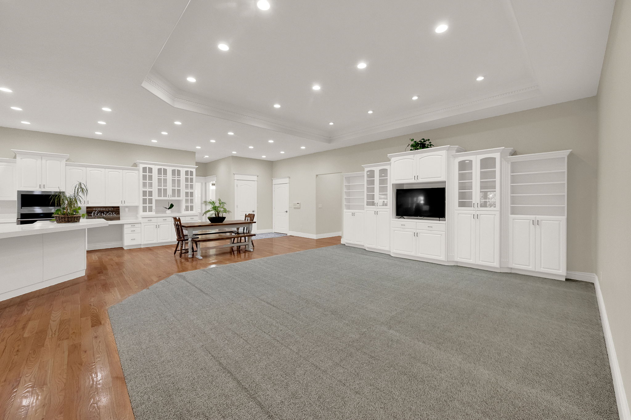 Expansive open-concept living space featuring a built-in entertainment center, recessed lighting, and crown molding