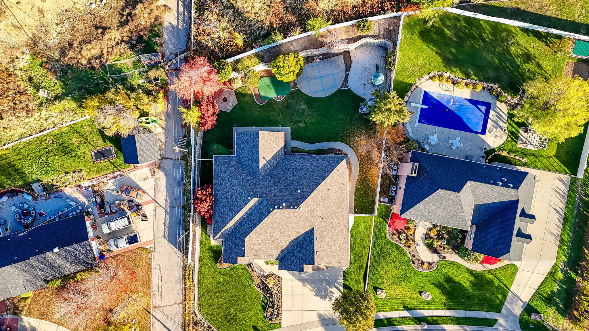 Expansive property featuring a multi-level roofline, extensive green lawn, concrete driveway, and a fenced swimming pool with surrounding patio
