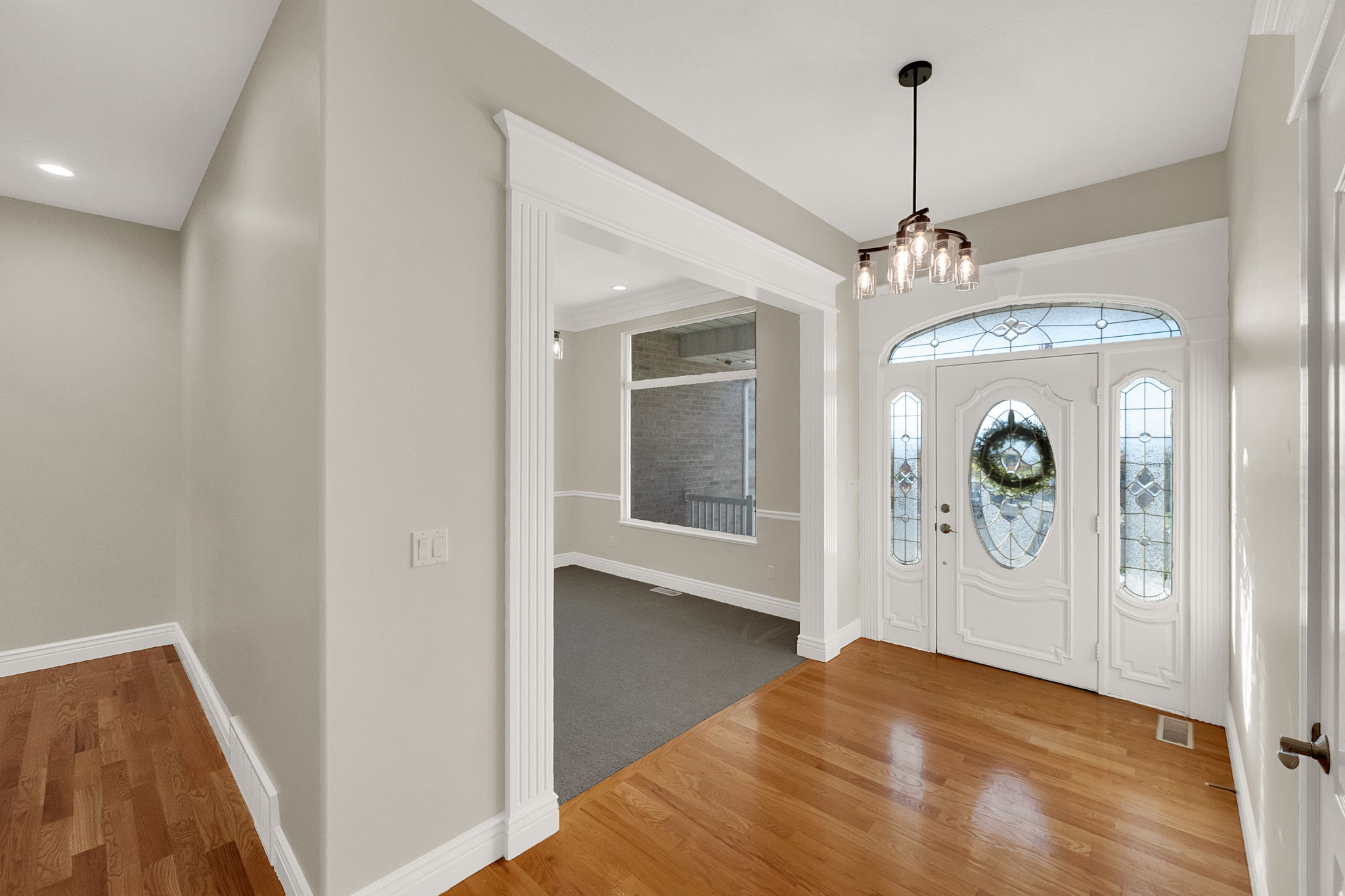 Entryway featuring hardwood flooring, a decorative front door with sidelights and transom window, and a contemporary chandelier