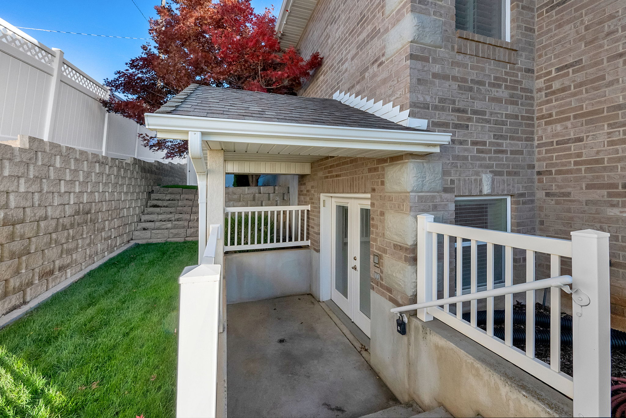 Brick exterior with a covered entry featuring white railings and dual glass-panel doors