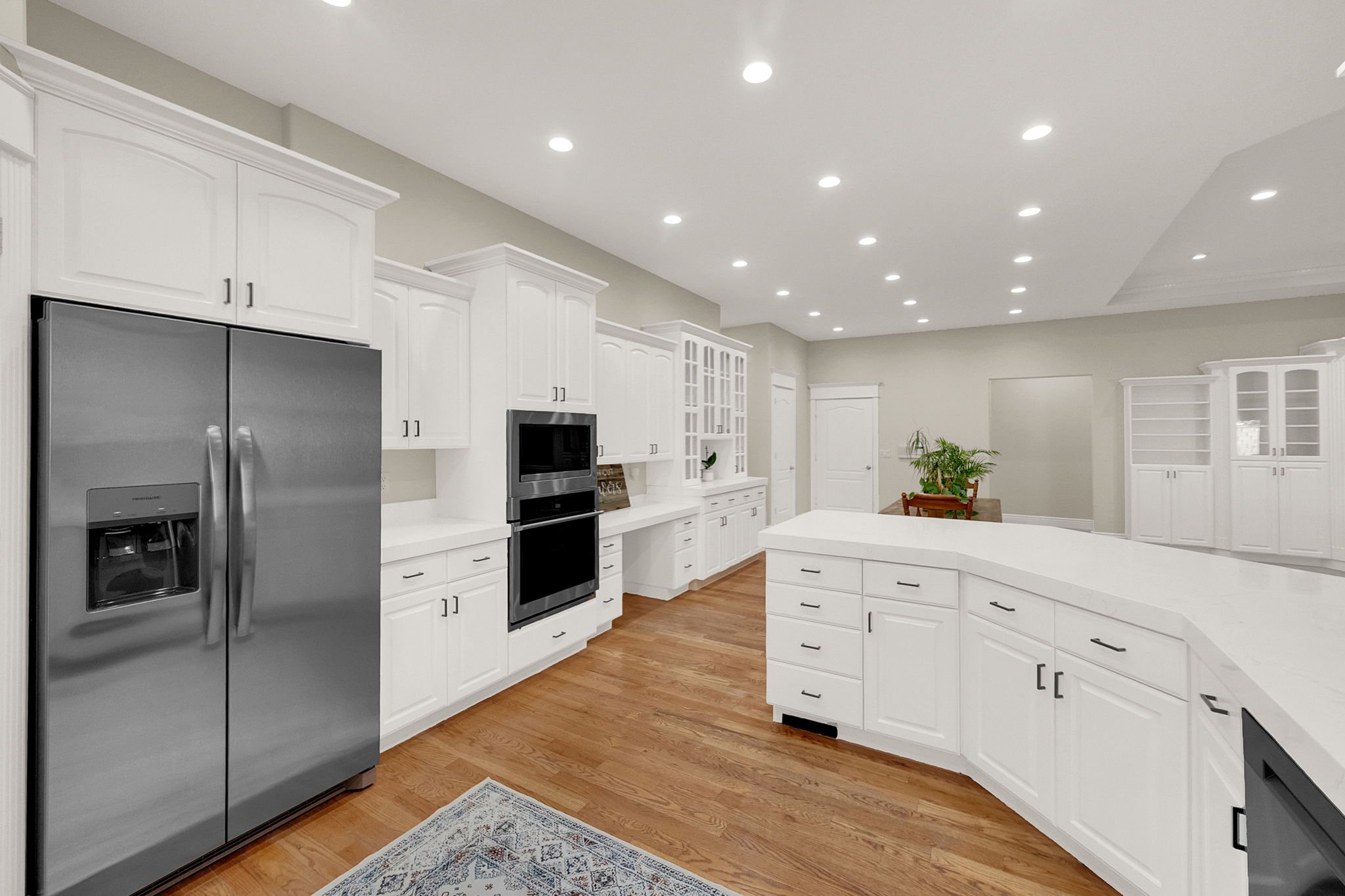 Expansive kitchen featuring white cabinetry, light-toned countertops, and wood-finish flooring
