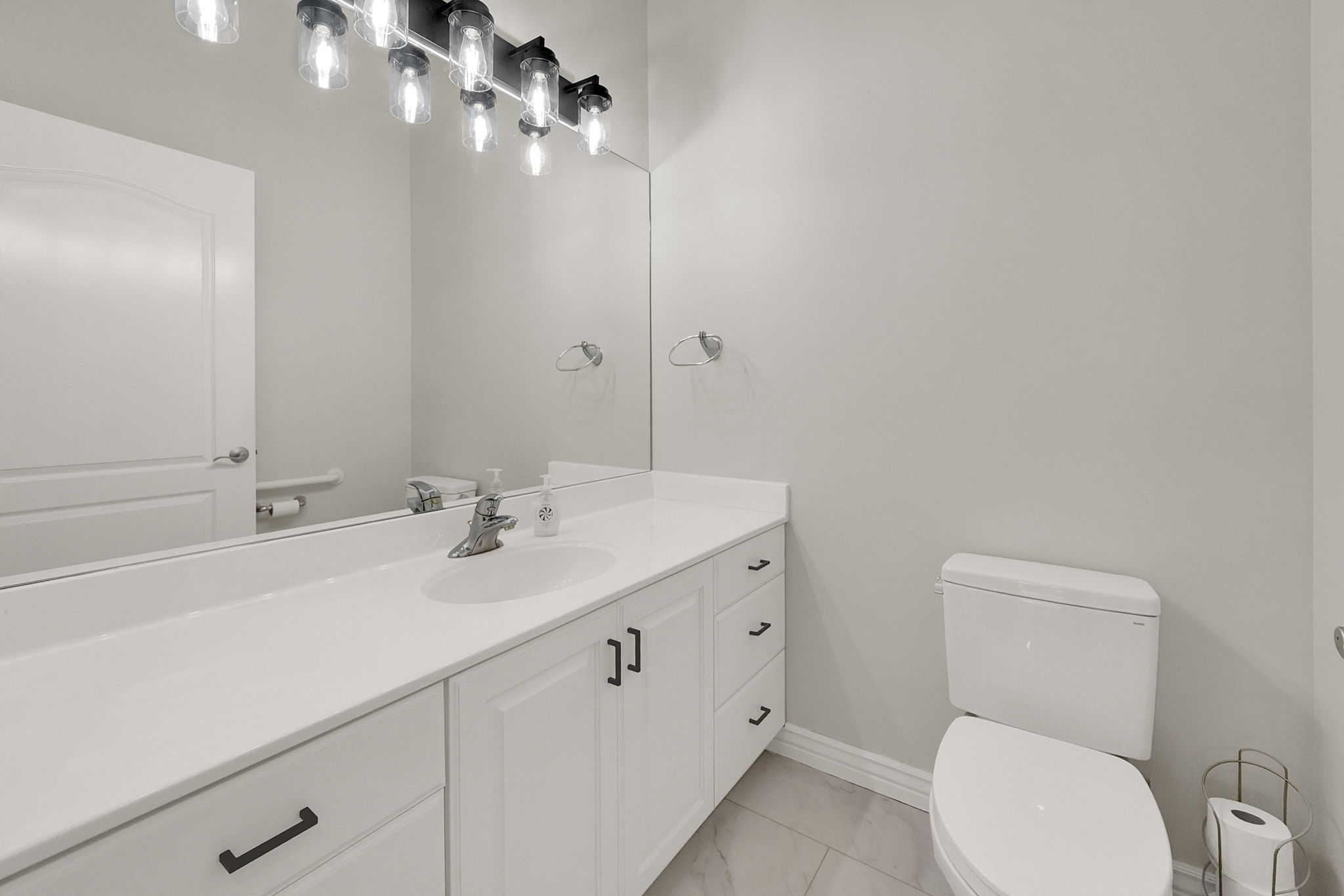 Bathroom vanity featuring white cabinetry, a single basin sink, and a coordinating countertop