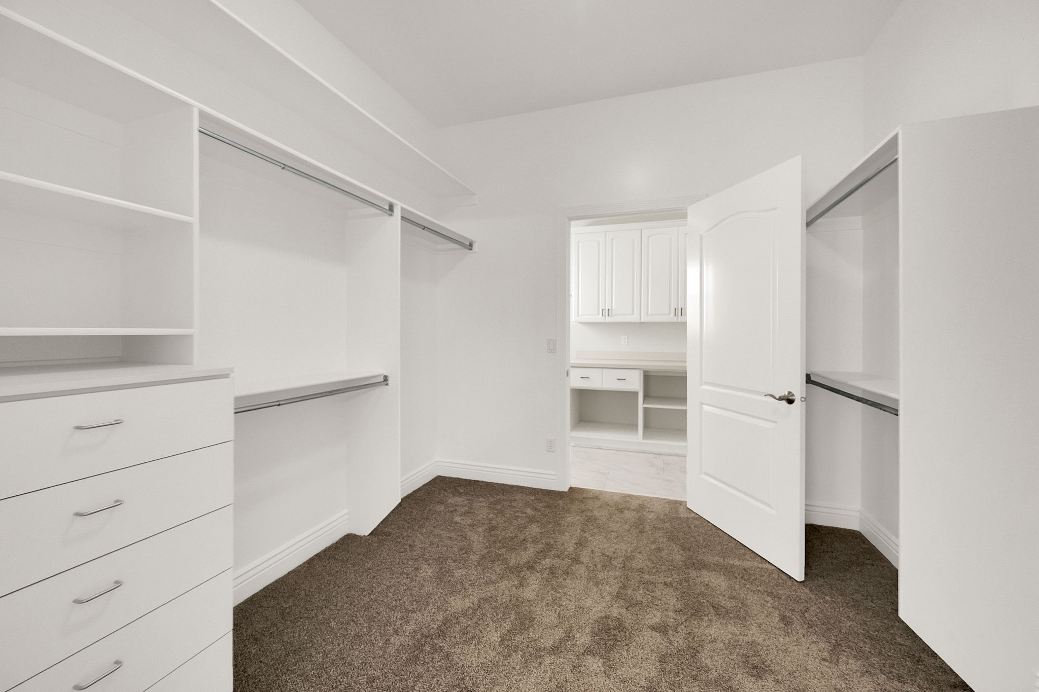 Walk-in closet featuring white built-in cabinetry, shelving, and hanging rods