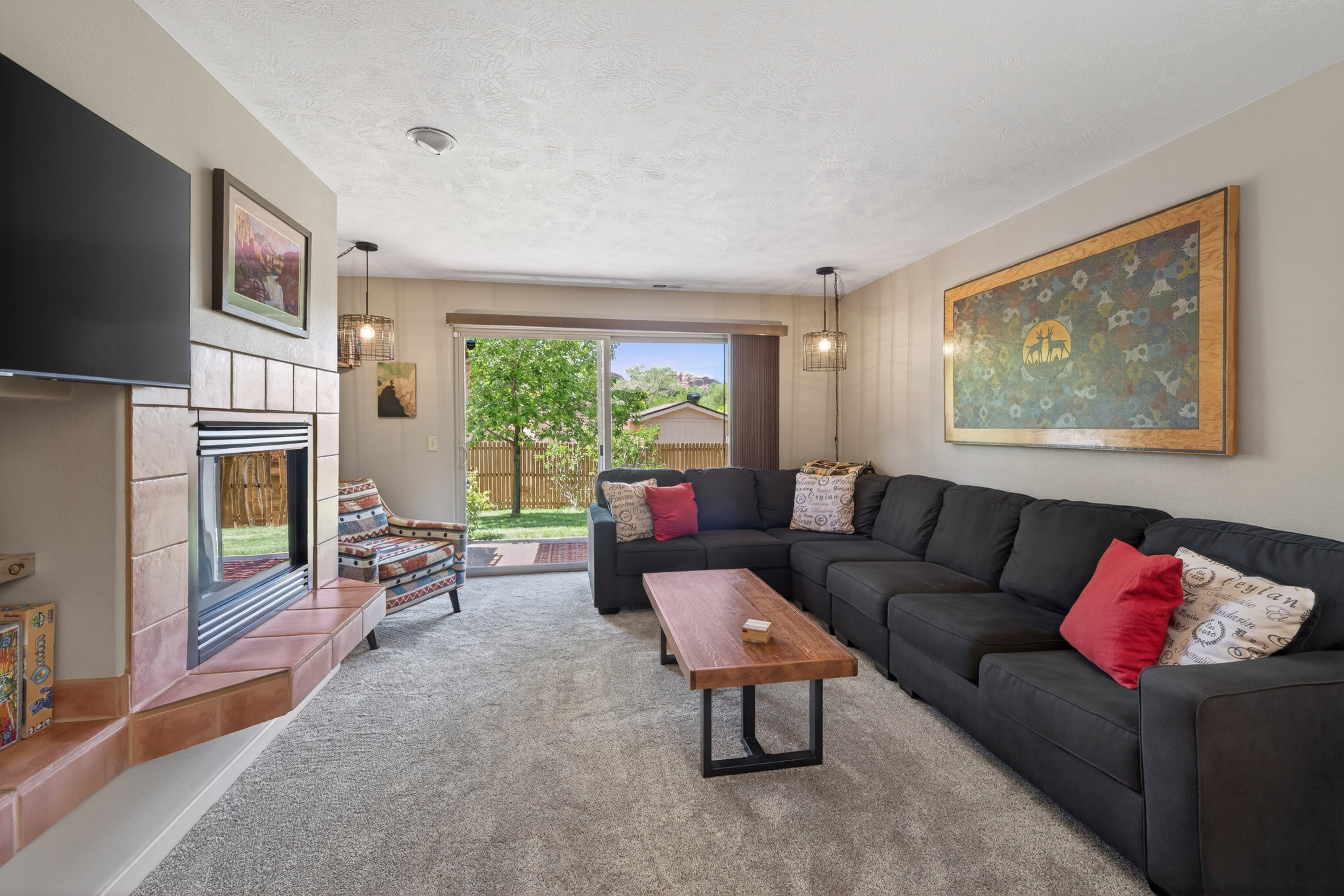 Living area featuring plush carpeting, a tiled fireplace with hearth, and a large sliding glass door
