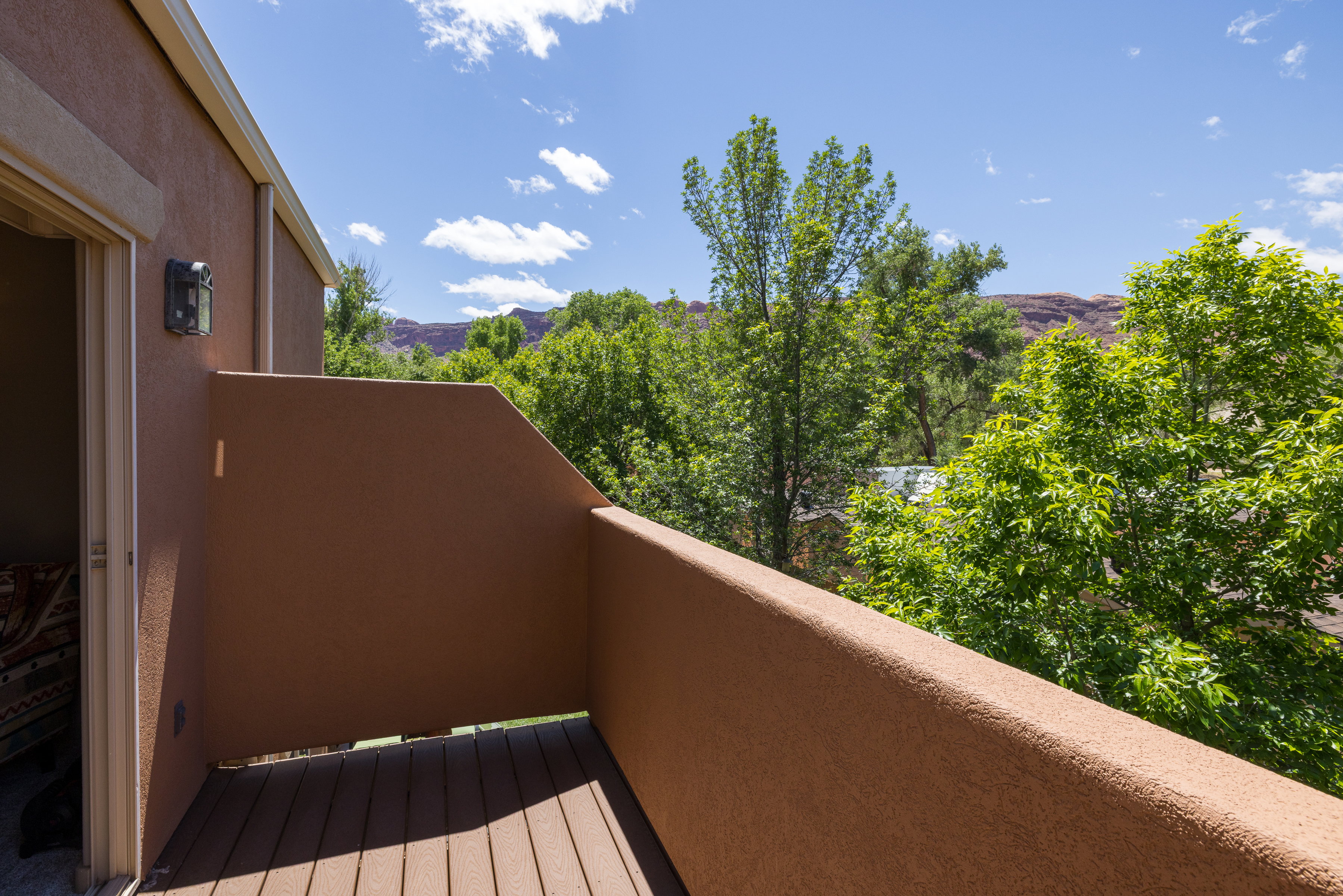 Private balcony featuring textured stucco walls and Trex flooring