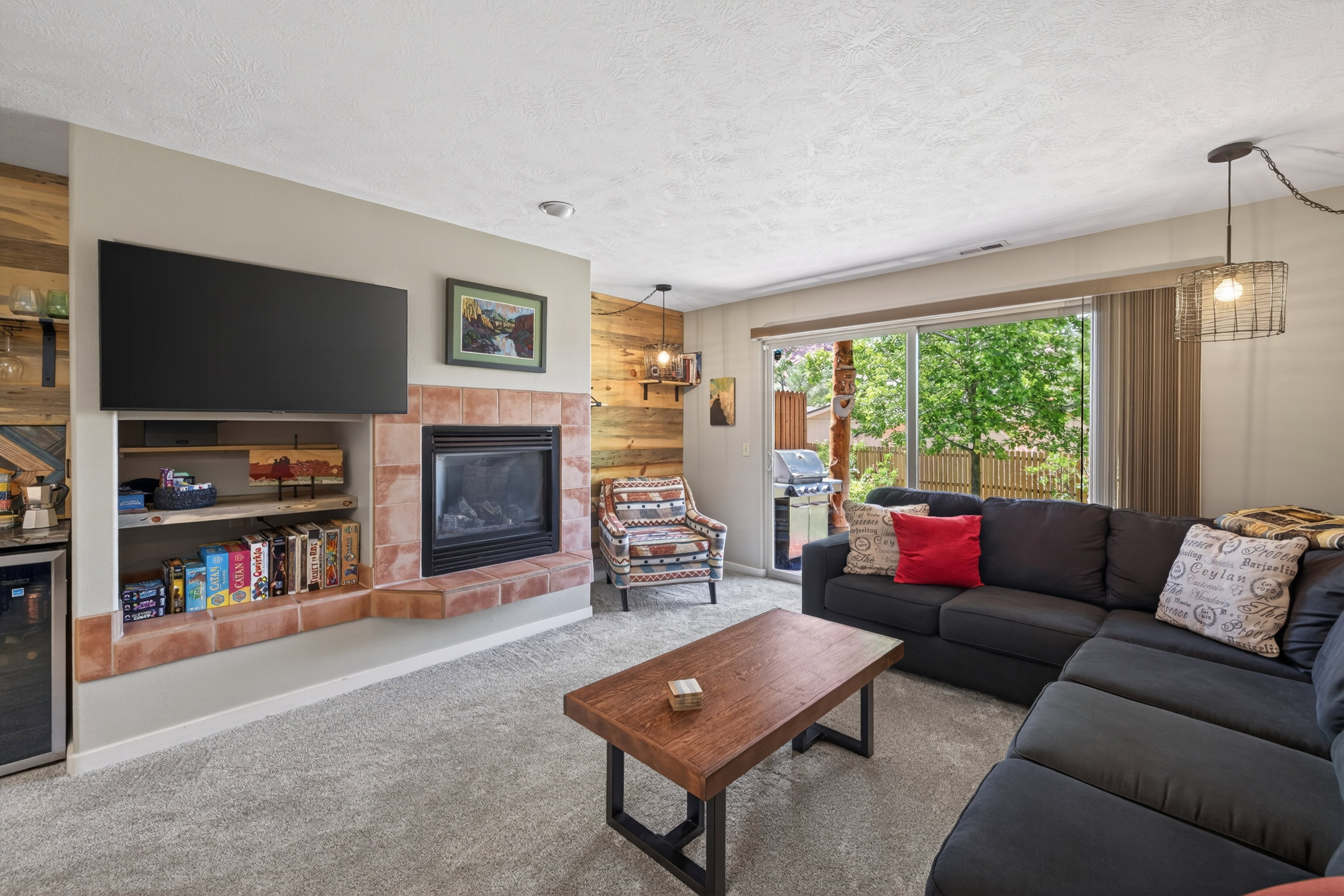 Living area featuring a tiled fireplace with an integrated media niche, light gray carpeting, and a glass sliding door leading to an outdoor space