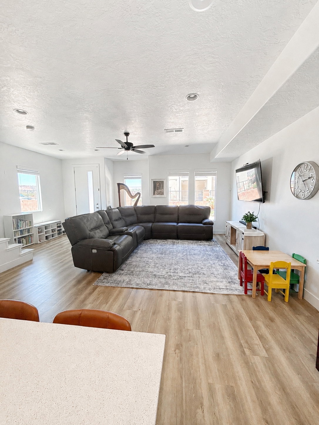 Spacious living area featuring light wood-finish flooring, recessed lighting, and a ceiling fan
