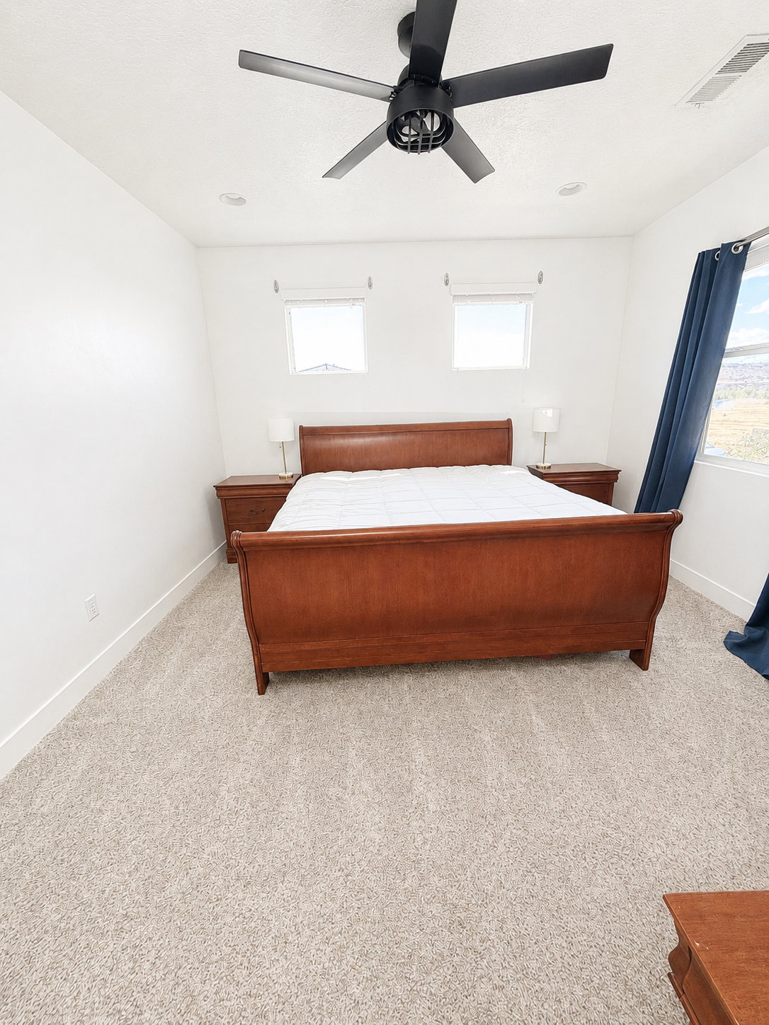 Spacious room featuring light carpeting, recessed lighting, a contemporary ceiling fan with black finish, and two high-set windows