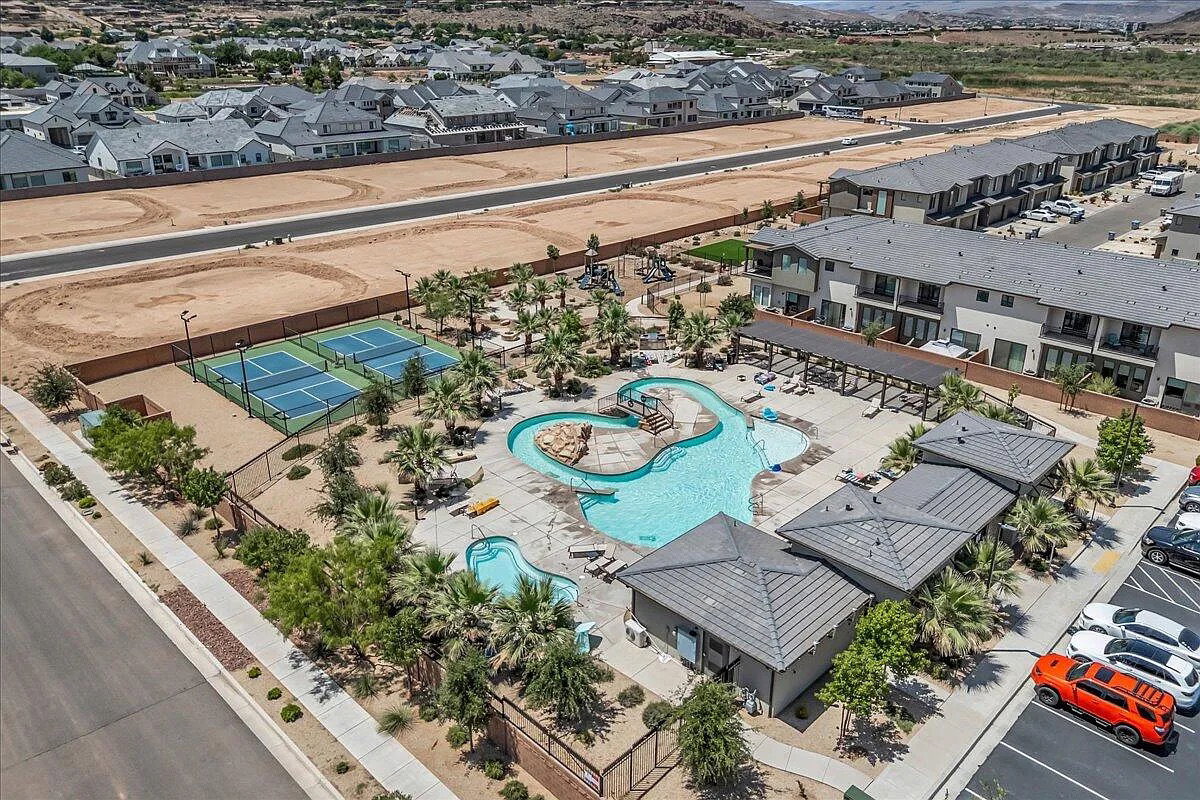 Community amenities featuring a resort-style pool with rock features, multiple tennis courts, shaded lounge areas, and dedicated parking