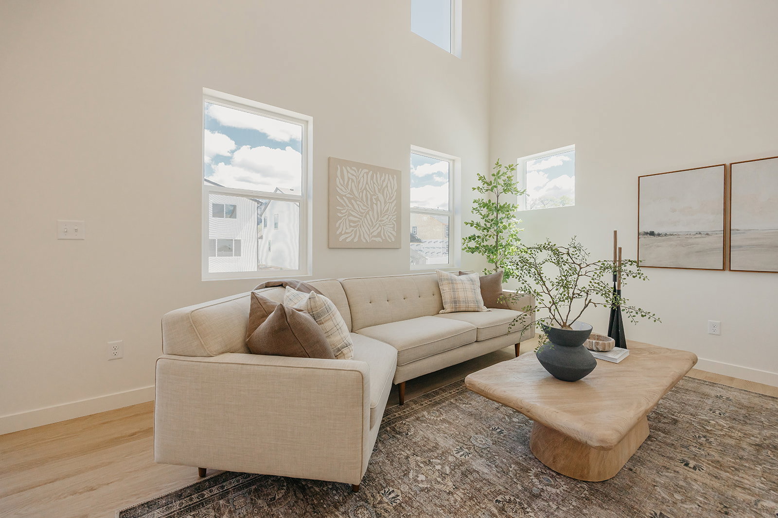 Living area featuring high ceilings, multiple windows, light-toned walls, and wood-finish flooring