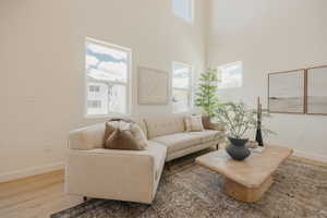 Living area featuring high ceilings, multiple windows, light-toned walls, and wood-finish flooring