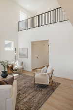 Spacious interior featuring a two-story ceiling, light wood-finish flooring, and a second-level balcony with black metal railings