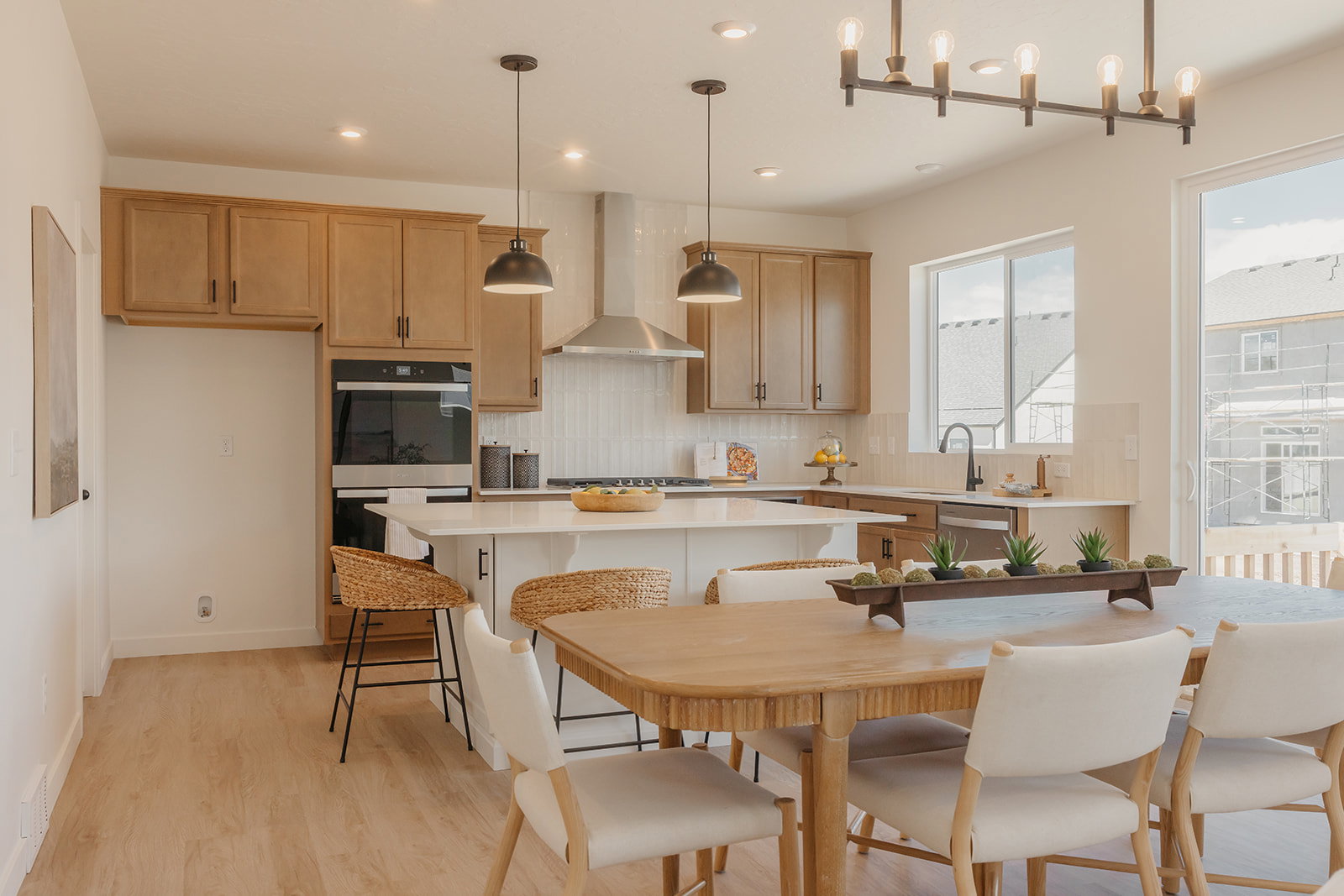 Modern kitchen featuring light wood-finish cabinetry, a large kitchen island with counter seating, and integrated stainless steel appliances including a built-in oven and microwave