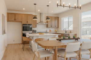 Modern kitchen featuring light wood-finish cabinetry, a large kitchen island with counter seating, and integrated stainless steel appliances including a built-in oven and microwave