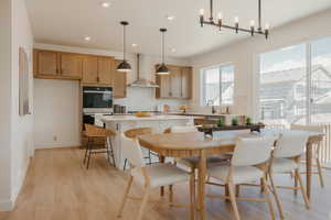Open-concept living area featuring wood-finish flooring, a contemporary dining chandelier, and large windows