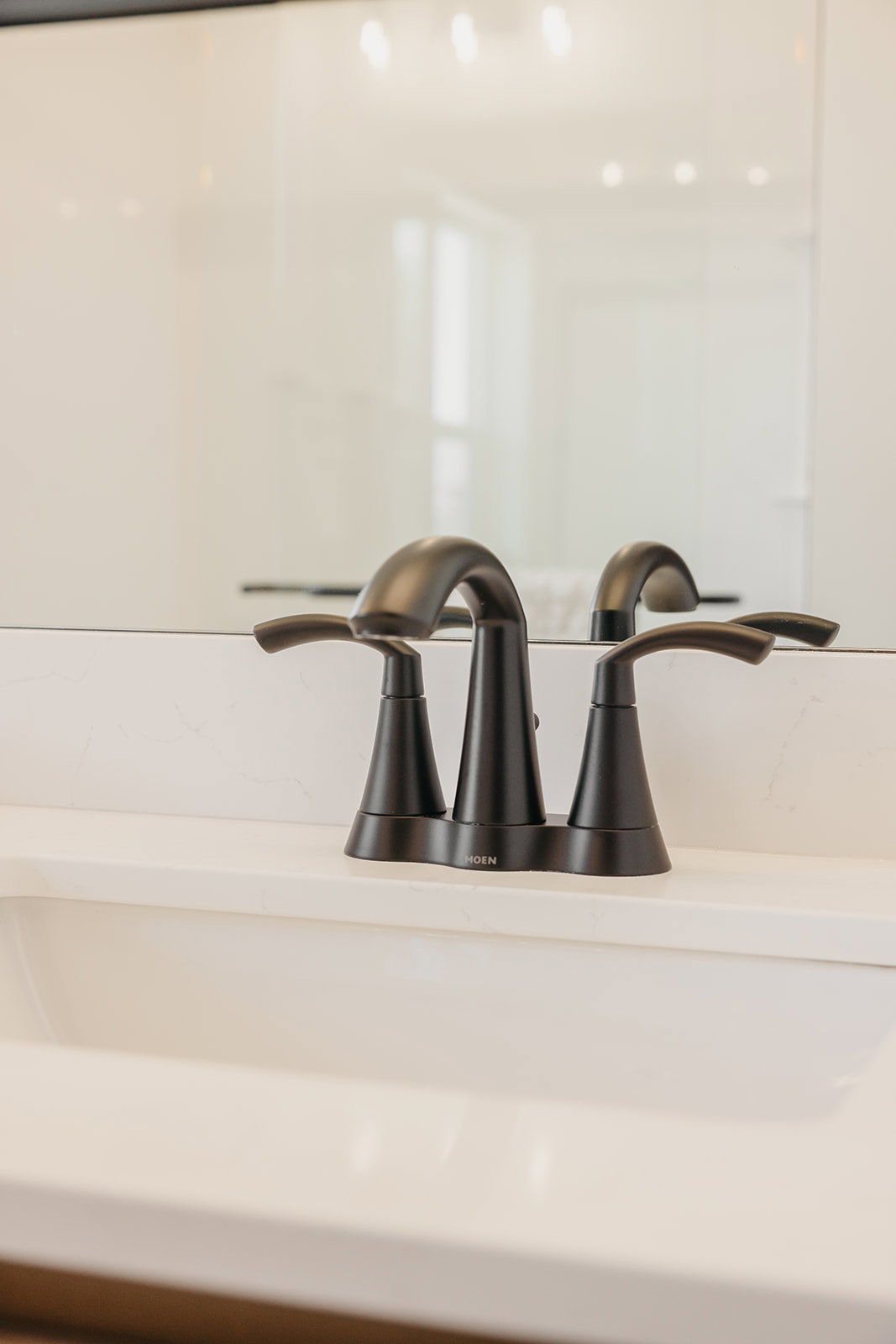 Matte black faucet with dual lever handles, set against a pristine white countertop and an integrated sink