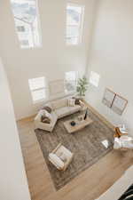 Two-story living area featuring tall ceilings, wood-finish flooring, and multiple windows