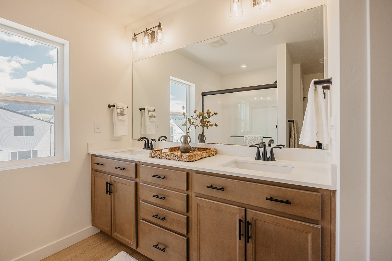 Double vanity with undermount sinks, light-toned wood cabinetry, and a quartz countertop