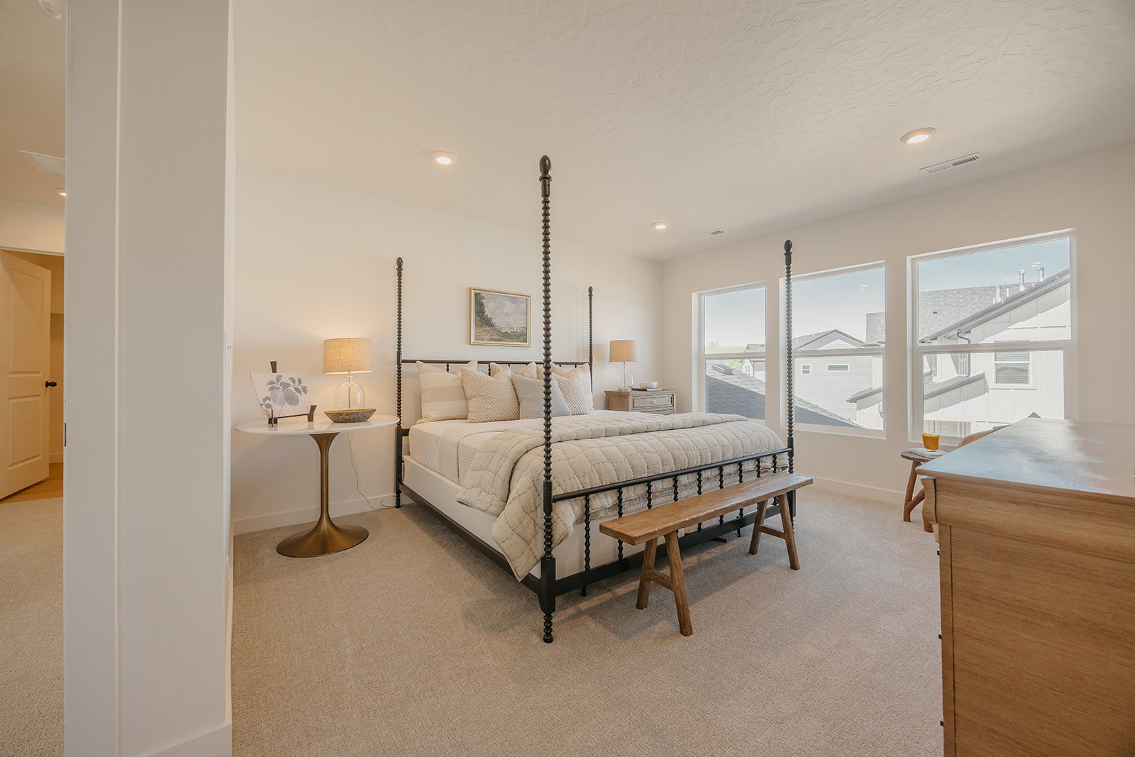 Spacious bedroom featuring light-toned carpeting, ample natural light from three large windows, recessed ceiling lighting, and a neutral wall palette