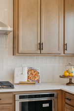 Kitchen featuring light wood-finish cabinetry with black hardware, white subway tile backsplash, and light-toned countertops