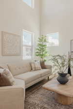Vaulted ceiling with high windows, main-level windows, wood-finish flooring, and a patterned area rug