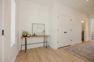 Bright hallway featuring wood-finish flooring, white baseboards, and a tall, narrow window