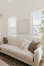 Living area featuring high ceilings, multiple large windows, and light wood-finish flooring