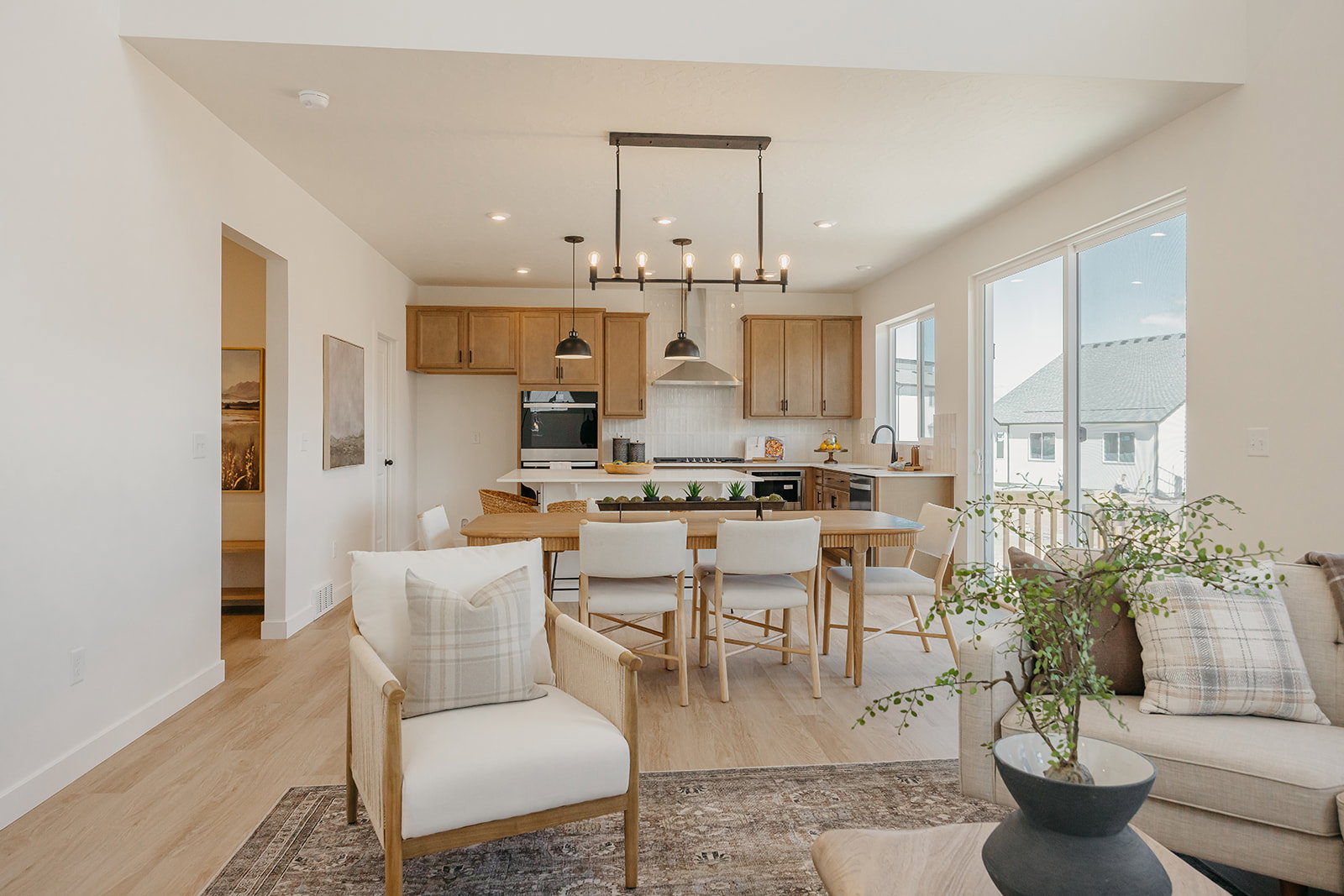 Open-concept living space featuring wood-finish flooring, recessed lighting, and a modern kitchen with light wood cabinetry