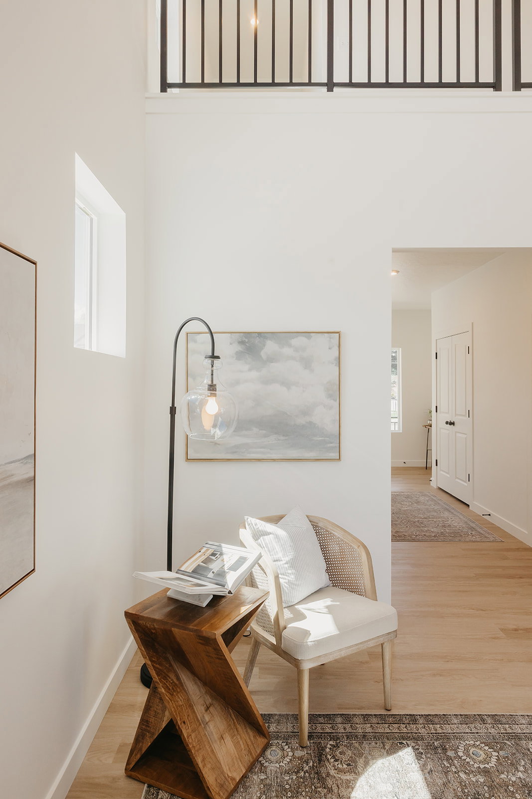Two-story entryway featuring wood-finish flooring, a contemporary black metal railing, and white walls