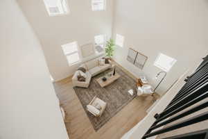 Two-story living area with high ceilings, multiple windows, light wood-finish flooring, and black metal staircase railing