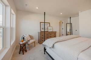 Spacious bedroom with light beige wall paint, two large vertical windows, recessed ceiling lighting, and light gray carpet flooring