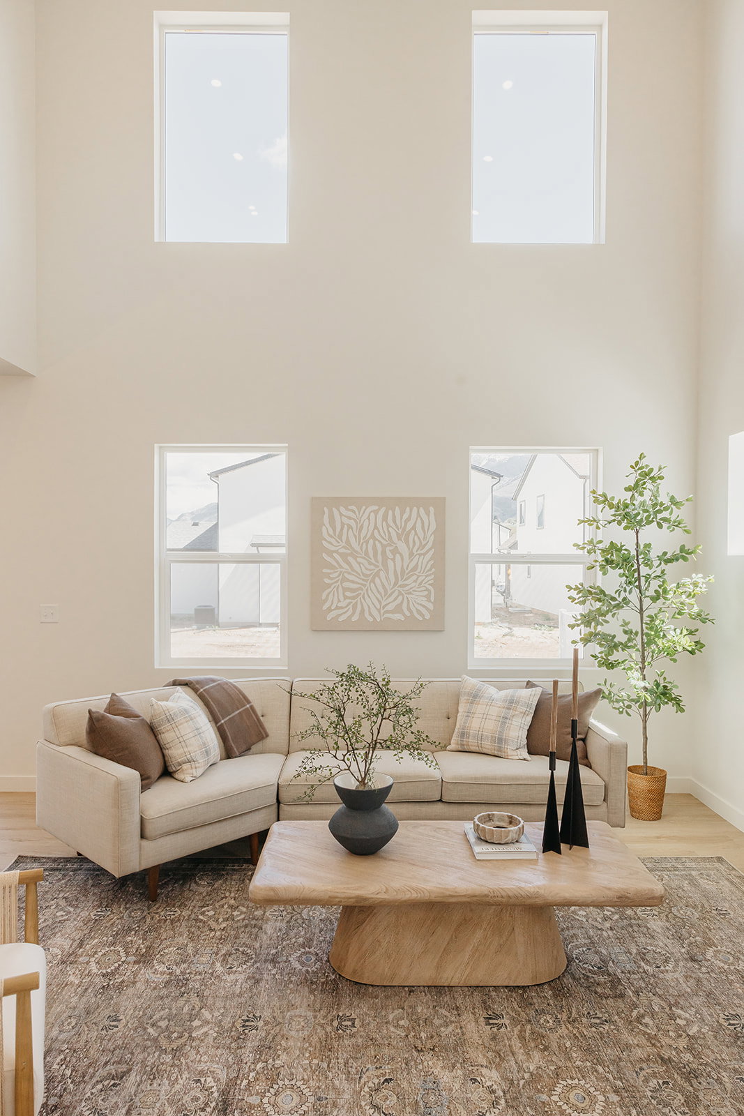 Great room featuring soaring ceilings, a two-story window arrangement, light wood-finish flooring, and a large area rug with a detailed pattern